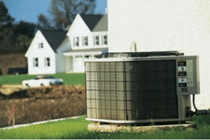 Air conditioning unit on exterior of home with other homes in the background.